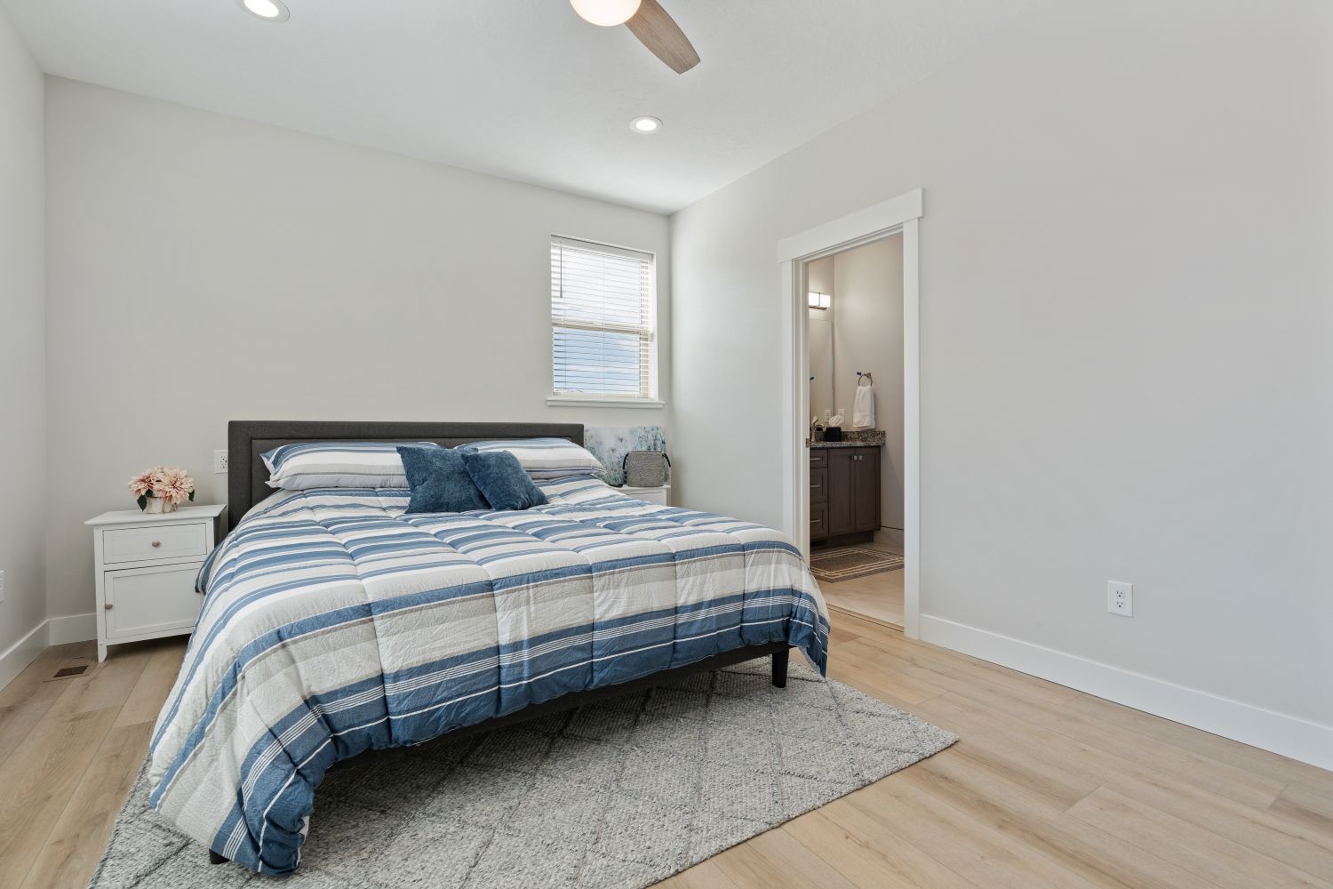 Bedroom with light wood finished floors, a ceiling fan, ensuite bathroom, and recessed lighting
