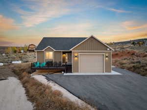 View of front facade featuring board and batten siding, asphalt driveway, a garage, and a shingled roof