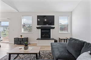 Living area with a glass covered fireplace, wood finished floors, and healthy amount of natural light
