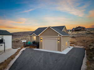 View of front of home with board and batten siding, a shingled roof, and asphalt driveway