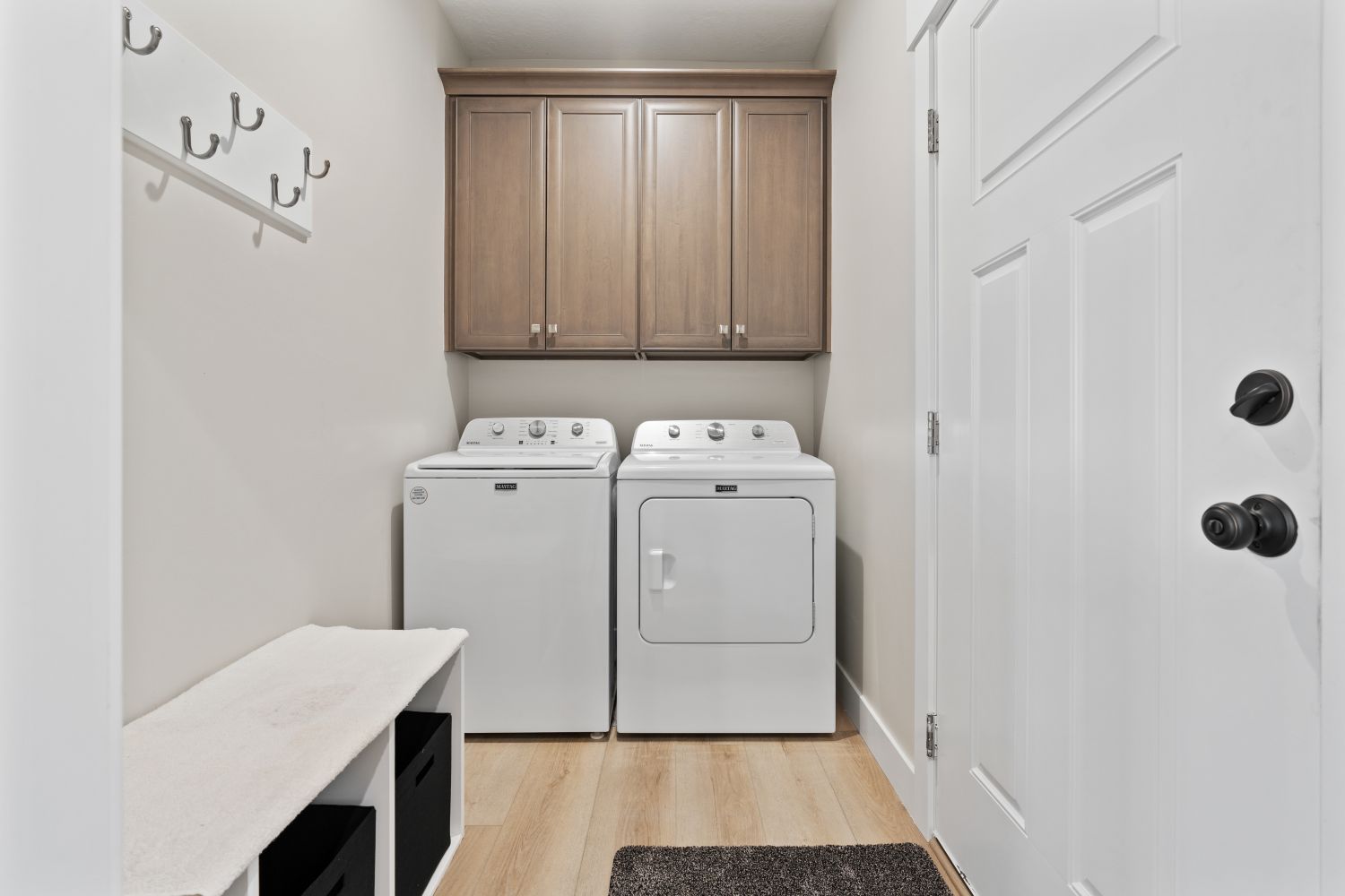 Washroom featuring separate washer and dryer, light wood-type flooring, and cabinet space