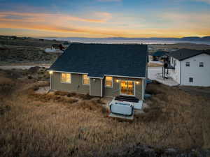 Back of house at dusk with a shingled roof, a mountain view, and a patio area