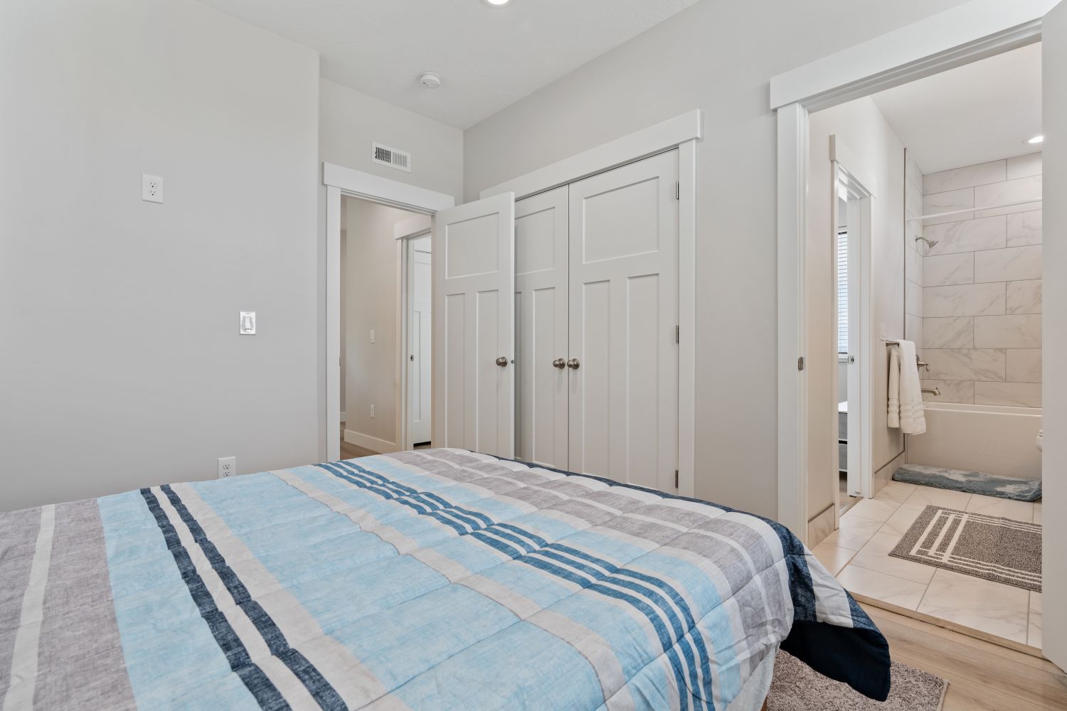 Bedroom featuring a closet, ensuite bath, and light wood-style flooring