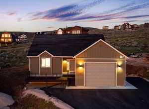View of front of property with board and batten siding, an attached garage, and asphalt driveway