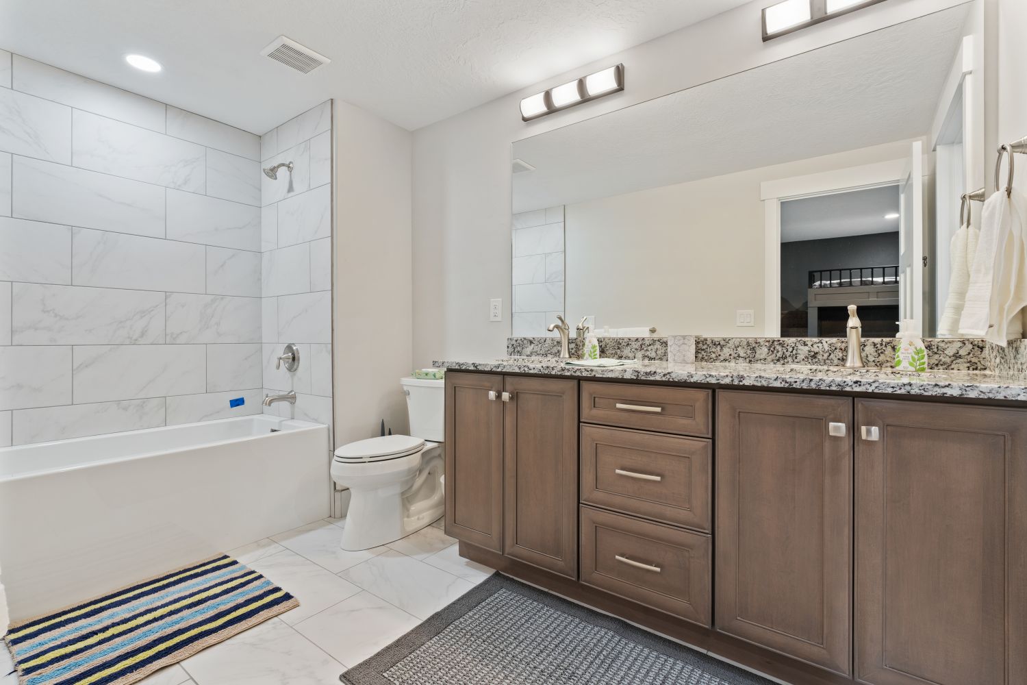 Bathroom featuring double vanity, bathing tub / shower combination, and light marble finish floors