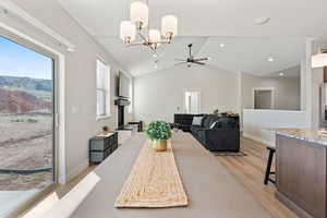 Dining room with a chandelier, lofted ceiling, light wood-style flooring, and ceiling fan
