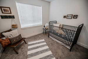 Carpeted bedroom with baseboards and a nursery area