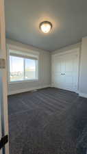 Unfurnished bedroom featuring dark carpet and a closet