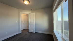 Unfurnished bedroom featuring dark carpet and baseboards