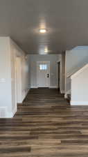 Entryway with dark wood finished floors, stairs, and a textured ceiling