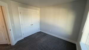 Unfurnished bedroom featuring dark colored carpet and a closet