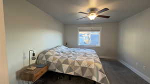 Bedroom with dark carpet and a ceiling fan