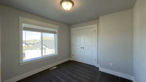Unfurnished bedroom featuring dark colored carpet and a closet