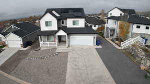 View of front facade with a residential view, board and batten siding, driveway, a porch, and solar panels