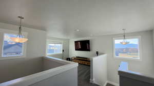 Hallway with an upstairs landing, plenty of natural light, and dark carpet