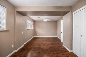 Unfurnished room with dark wood-style flooring, ceiling fan, and a textured ceiling