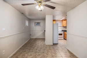 Spare room featuring a textured ceiling, ceiling fan, a wall mounted AC, and light tile patterned floors