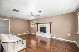 Living area featuring ceiling fan, dark wood-style flooring, and a fireplace