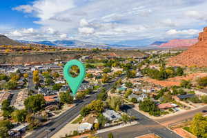 Aerial view of property and surrounding area featuring a mountain backdrop and nearby suburban area