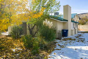 Snow covered property featuring a metal roof and a chimney