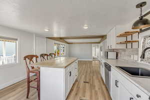 Kitchen featuring a breakfast bar, white cabinetry, a kitchen island, butcher block counters, and light wood-style floors