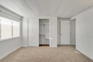Unfurnished bedroom featuring light carpet and a closet