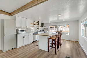 Kitchen with white cabinetry, wood counters, a breakfast bar area, a center island, and healthy amount of natural light