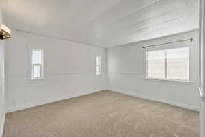 Spare room with light carpet and baseboards