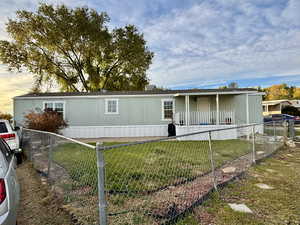 Manufactured / mobile home featuring a fenced front yard and covered porch