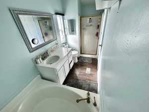 Bathroom featuring a garden tub, vanity, a shower stall, and dark wood-type flooring