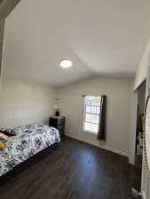 Bedroom with vaulted ceiling and dark wood-type flooring