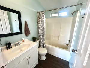 Bathroom with vanity, shower / tub combo with curtain, and dark wood-style floors