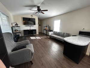 Living area featuring lofted ceiling, dark wood-type flooring, and ceiling fan