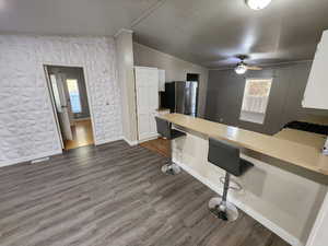 Kitchen featuring a breakfast bar area, a peninsula, light countertops, white cabinets, and lofted ceiling