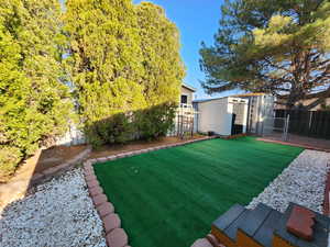 Fenced backyard featuring a shed and a gate