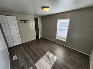 Unfurnished bedroom with dark wood-style flooring and a closet