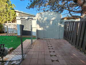 Fenced backyard featuring a storage shed, a patio, and a gate