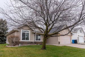 View of front facade with stone siding, a front yard, and concrete driveway