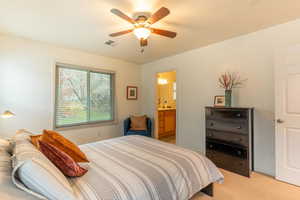 Bedroom with light carpet, ceiling fan, and ensuite bathroom