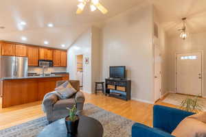 Living area with light wood-style floors, a ceiling fan, high vaulted ceiling with back pantry shelving and washer and dryer.