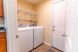 Laundry room with light tile patterned floors and separate washer and dryer  Garage door.