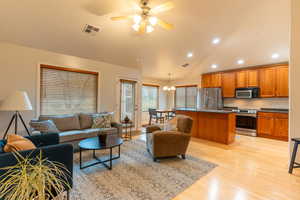 Living area featuring light wood-style floors, a chandelier, a ceiling fan, recessed lighting, and high vaulted ceiling, semi formal dining, and patio door,