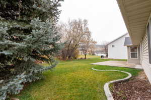 View of grassy yard featuring a patio area