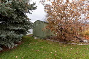 View of side of home featuring a yard and a shed