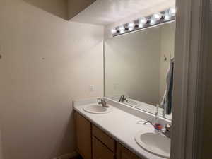 Full bathroom with double vanity and a textured ceiling