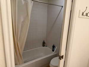 Bathroom featuring shower / tub combo with curtain and toilet