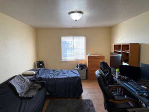 Bedroom featuring a textured ceiling, an office area, and wood finished floors
