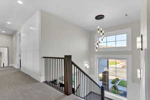 Corridor featuring carpet, an upstairs landing, and a chandelier