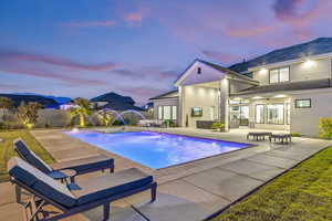 Pool at dusk with a patio area, a fenced backyard, outdoor lounge area, and a ceiling fan