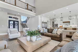 Living room featuring a chandelier, recessed lighting, a high ceiling, french doors, and stairway